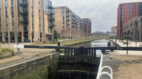 A set of locks giving way to canal running between multi-storey buildings. They make up part of the Manchester, Bolton and Bury Canal, which has been restored at Middlewood Locks in Salford.