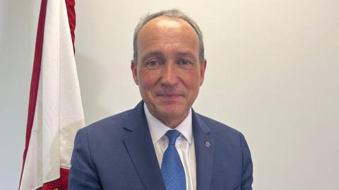 Lyndon Farnham in a blue suit and tie with white shirt
