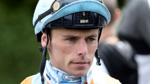 A close-up of a jockey wearing a helmet with a serious facial expression