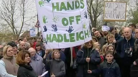A large crowd dressed in coats holding protest cards
