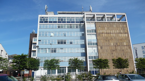 The exterior of Blackburn Telephone Exchange building on Jubilee Street, Blackburn, on a sunny day. It is a building several storeys high with glass windows on one side and brick on the other.