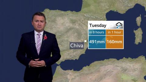 Matt Taylor stands in front of a map of Spain showing Tuesday's rainfall totals