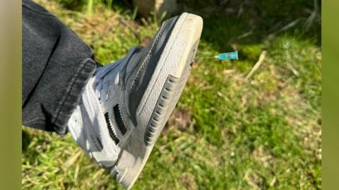 Shoe with a needle embedded in it