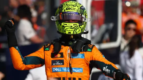 The McLaren of Lando Norris is pushed into position by his mechanics on the grid before the start of the Hugarian Grand Prix