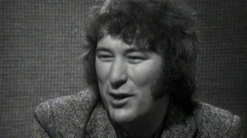 Seamus Heaney sits in a studio.