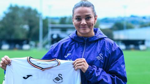 Nia Jones holds up a Swansea City shirt