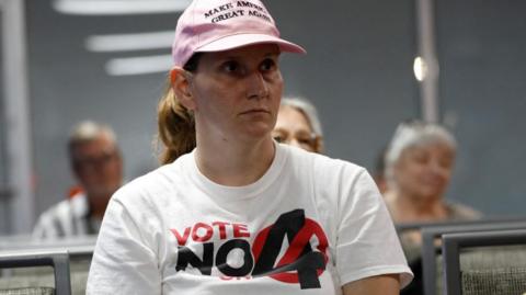 Ashley Urban, wearing a 'Vote No' on Florida Amendment 4 T-shirt, which addresses the state’s abortion bill, prays with other parishioners 