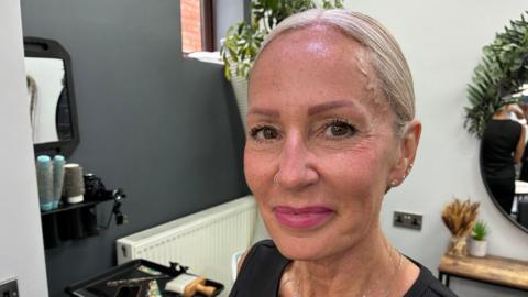 A woman with blonde hair and pink lipstick in a hair salon