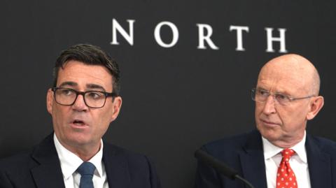 Andy Burnham and John Healey under a sign saying 10 North