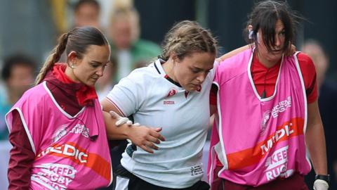 Jenni Scoble (C) is helped off against Canada