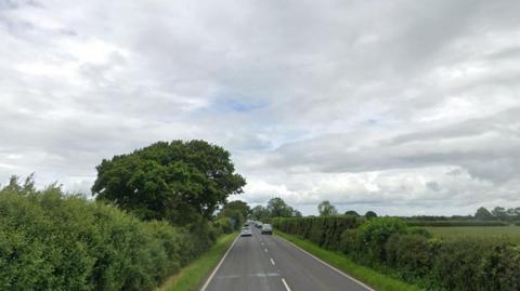 The A59 road, a country road with two carriageways. A grass embankment can be seen at the side of the road.