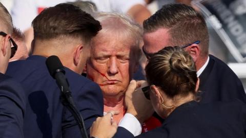 Donald Trump surrounded by staff