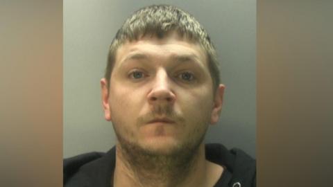 A blond man wearing a black jacket. 