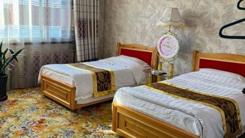 Two beds in a hotel room, which has a golden carpet