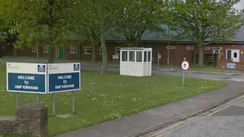 Entrance to HMP Kirkham has a large blue and white sign which reads: "Welcome to HMP Kirkham".