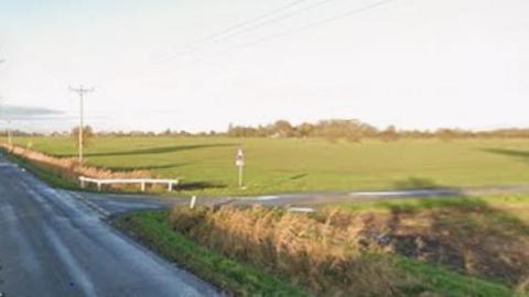 A junction of two country sides surrounded by fields.