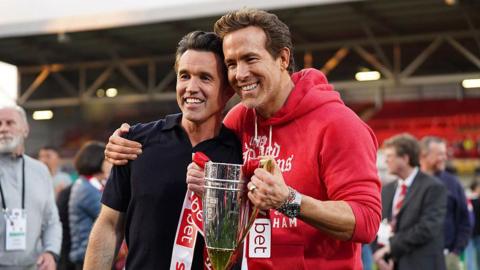 Rob McElhenney a Ryan Reynolds yn dal tlws ar ôl ennill dyrchafiad o'r Adran Gyntaf i'r Bencampwriaeth yn 2025