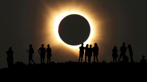 A group of people in shadow viewing a solar eclipse