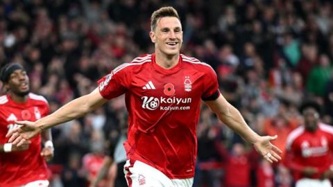 Chris Wood celebrates a goal, smiling with his arms spread wide