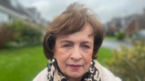 Diane Dodds who has short brown hair and is wearing a cream jacket. 