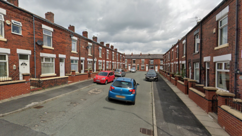 A street view image of Longden Road. There are houses lining each side of the street and cars parked on the pavements.