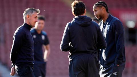 Kieran McKenna in discussion with his Ipswich players on the pitch at St Mary's