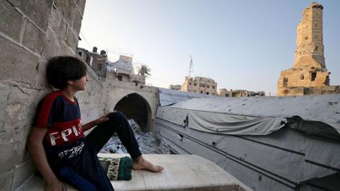 Boy on the roof of a building with a skyline behind