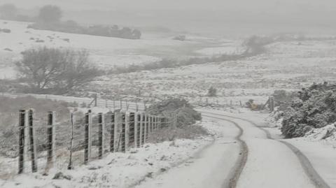 A road near Jamaica Inn set in the moors is covered in snow.