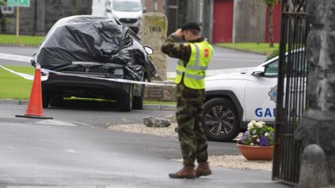 A car wrapped in black plastic and a garda car at the scene at Renmore Barracks in County Galway, after an army chaplain was stabbed. A uniformed soldier stands by the gate in a high-vis jacket