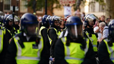 Police officers look on as people attend the 'Enough is Enough' protest in Whitehall