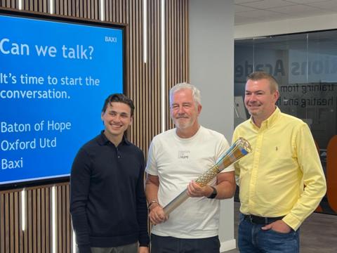From left to right Ryan Maher, Mike McCarthy and Paul Haynes posing for a picture. They are smiling. Mr McCarthy is holding a baton. They are looking away from the camera. 