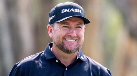 A smiling Graeme McDowell wears a dark cap and open-necked shirt
