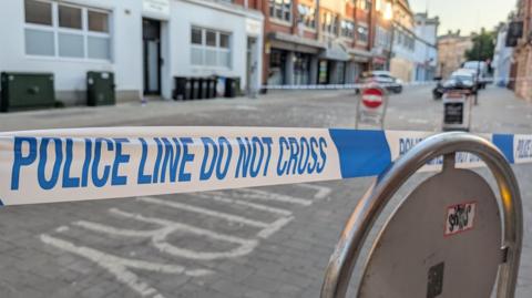 A high street partly cordoned off with police tape
