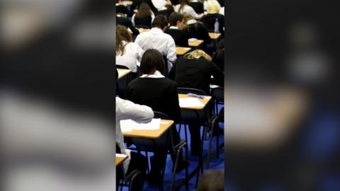 Back view of a row of students taking an exam in a school hall