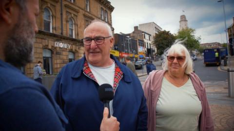 Man an woman answer question on street