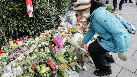 A woman lays a flower at the mourning site after a car rammed into a rally in Munich, German