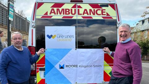 Paul Samrah and his traveling companion stand alongside one of a fleet of ambulances they are driving to the Ukrainian city of Lviv 