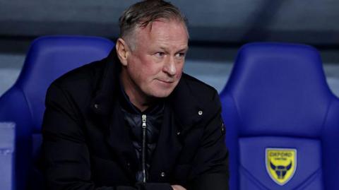Blackburn Rovers boss Michael O'Neill sits in the Oxford United dugout at the Kassam Stadium