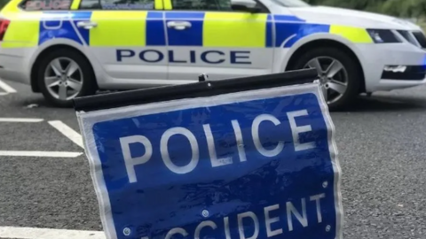 A police road stop, a blue accident sign in the foreground and a police car in the background