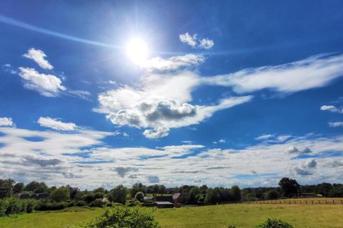 Bright sunshine and scattered clouds over a rural landscape in Harlestone, Northamptonshire