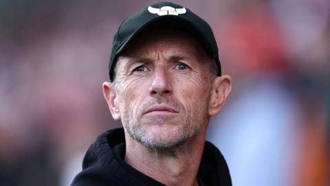Gary Rowett watches an Oxford United game in an Oxford United cap