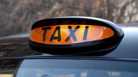 An orange 'Taxi' sign on top of a cab.