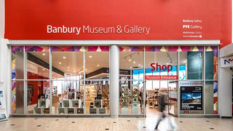 The shop entrance to the museum, which has floor to ceiling windows revealing objects within.