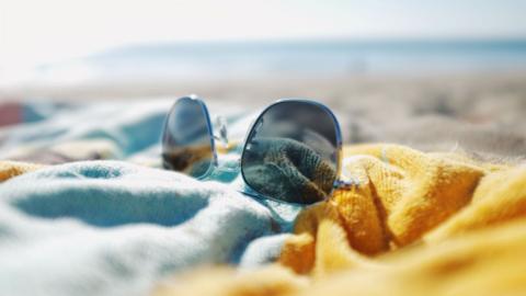 Sunglasses on a towel on a beach