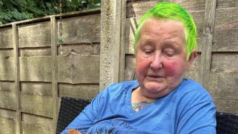 The victim of a crash, wearing a blue T-shirt and with green hair