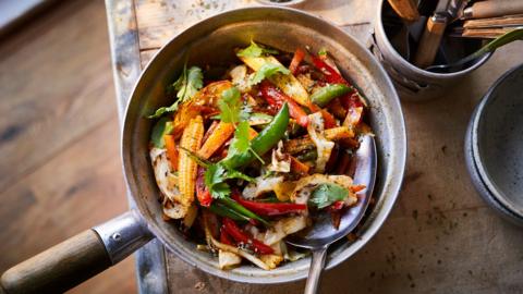 Top down view of stir fry jalfrezi in a wooden handled pan