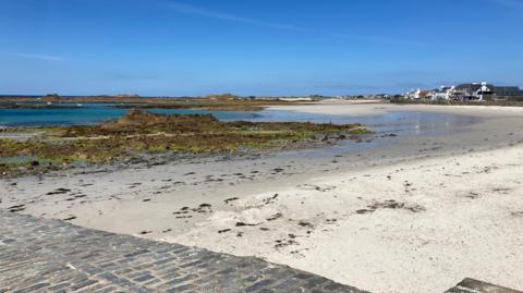 The picture shows Cobo beach on Guernsey's west coast on a sunny day with a blue sky