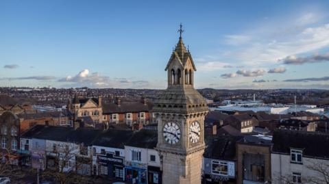 An aerial view of the top of a clock tower standing in the middle of a town.