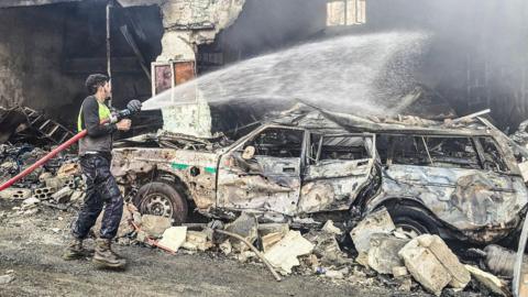 A firefighter existinguishes a fire at the site of an Israeli air strike in a Lebanese village