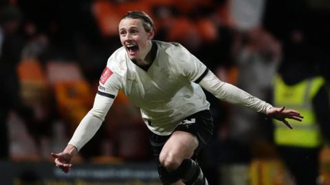 Ben Waine runs with his mouth open and his arms outstretched in celebration after scoring